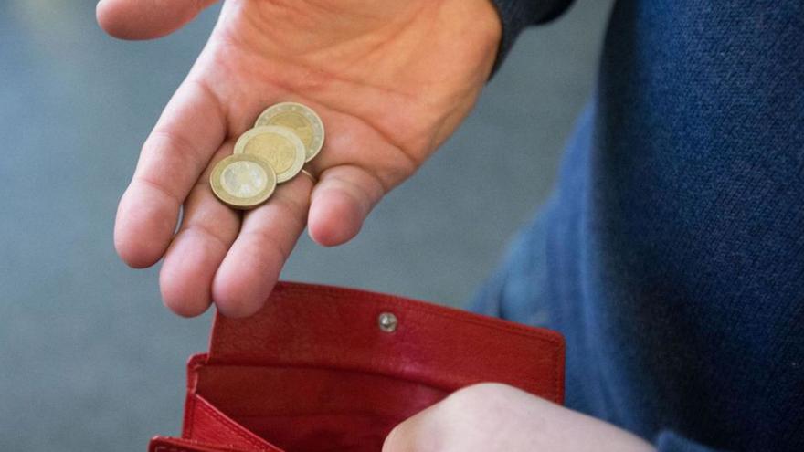 Un hombre guarda unas monedas en su cartera.