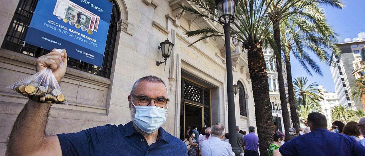 Un hombre con una bolsa llena de pesetas frente al Banco de España, cerca de la plaza del Ayuntamiento de València.  | GERMÁN CABALLERO