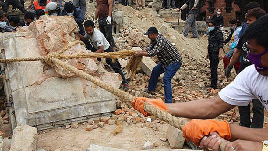 un grupo de nepalíes levantan una roca en Bhaktapur.