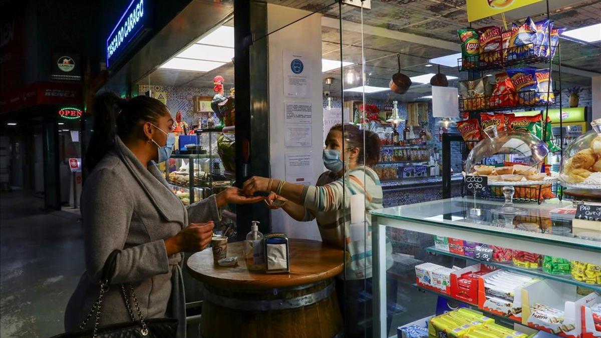 Una mujer compra un café en un local parcialmente abierto en Oporto (Portugal).