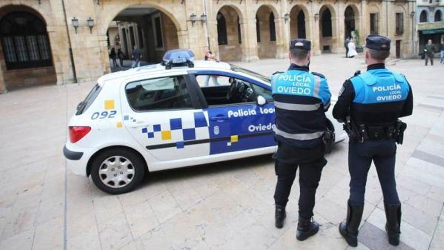 Dos de los agentes del dispositivo &quot;antibotellón&quot; de la Policía Local hacen guardia ayer en el plaza del Ayuntamiento frente a su coche patrulla.