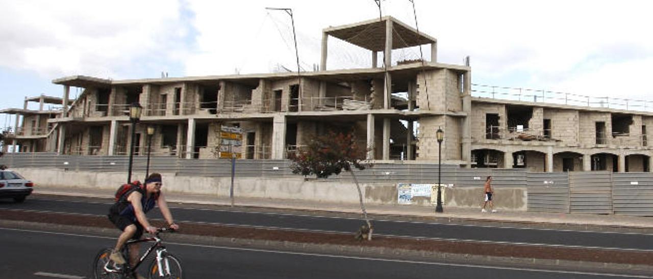 Un ciclista circula por delante de las obras inacabadas de un hotel a la entrada de la localidad turística de Corralejo.