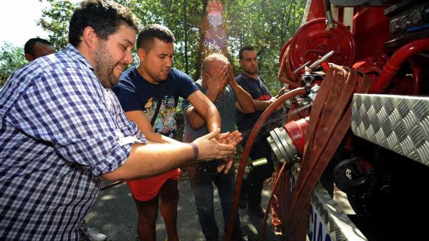 Los vecinos se refrescan en uno de los camiones motobomba enviados a Xiabre. // Iñaki Abella