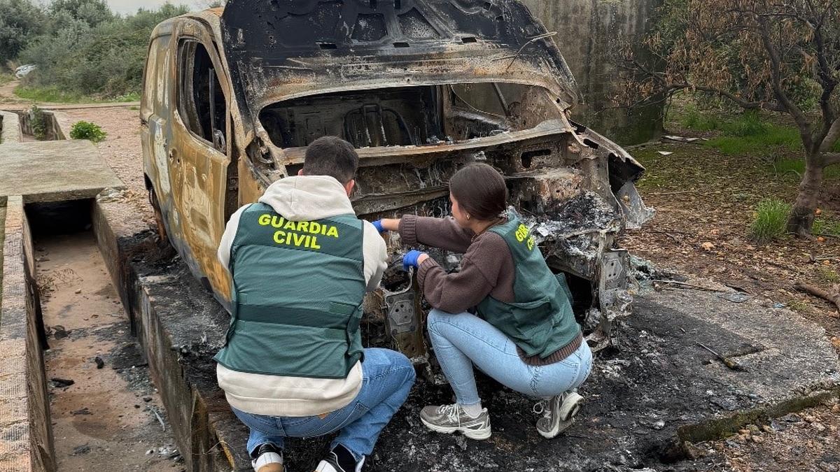 Agentes de la Guardia Civil inspeccionan el vehículo incendiado.