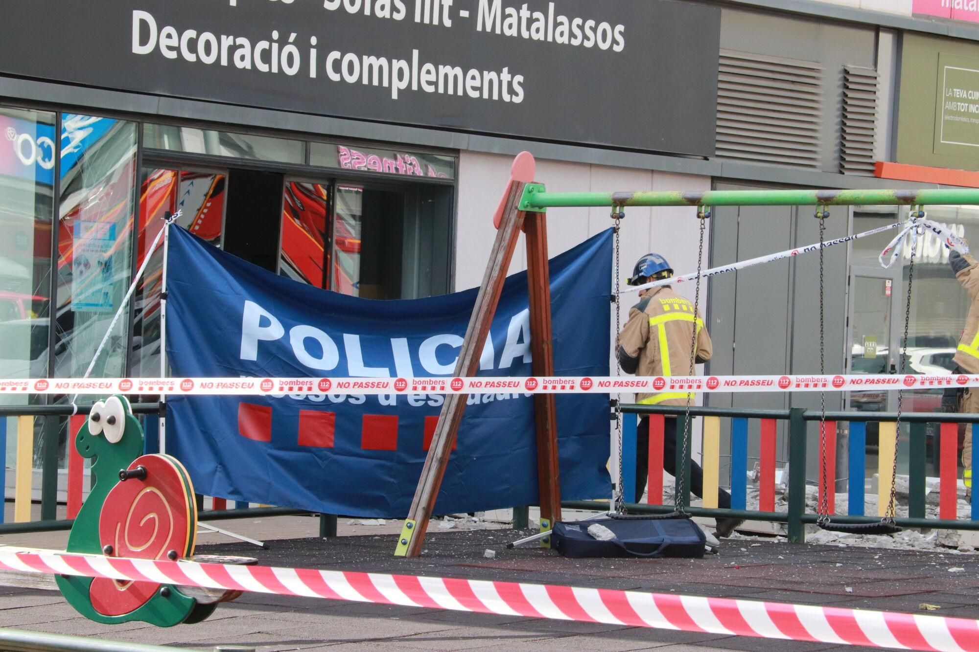 Un bomber al costat d'un tendal dels Mossos d'Esquadra al punt on s'ha desprès un plafó de formigó al centre comercial Via Sabadell que ha atrapat una persona