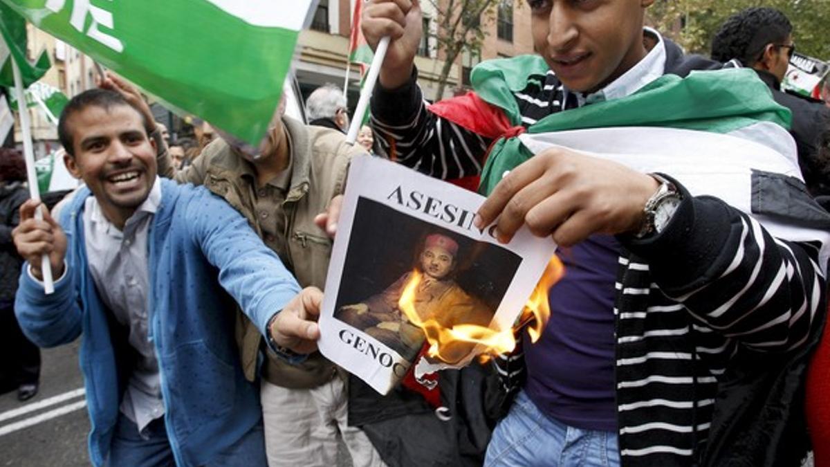 Dos ciudadanos marroquís queman una foto del rey de Marruecos, Mohamed VI, durante la manifestación para condenar el asalto al campamento saharaui de El Aaiún, hoy en Madrid.