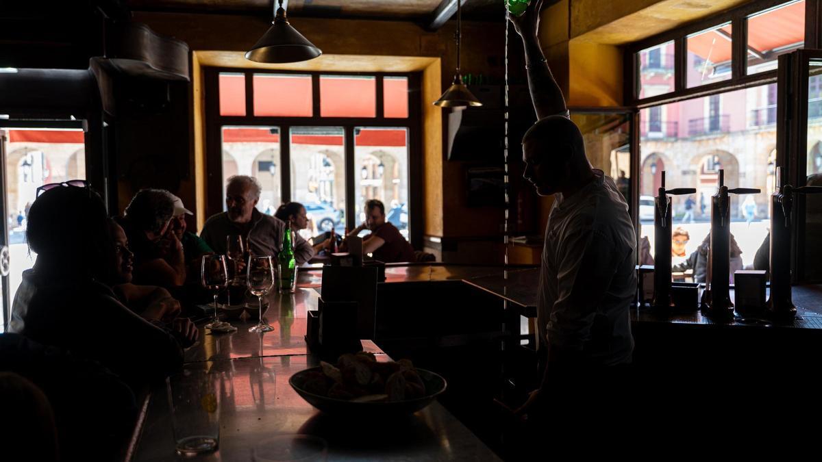 Un camarero sirve sidra en un bar durante el apagón.