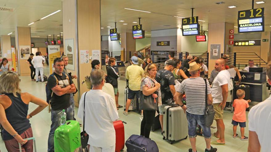 Los pasajeros de varios vuelos de Vueling, ayer en la cola de facturación.