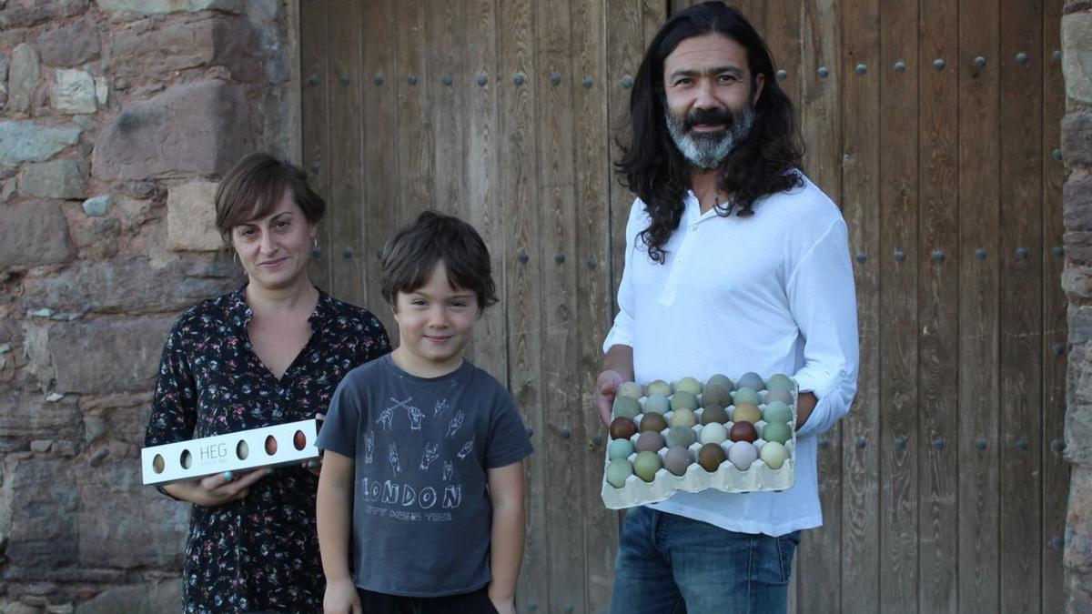 Nereida García, Toni Martínez i el seu fill, René, mostren els ous de colors en un dels portals de la masia