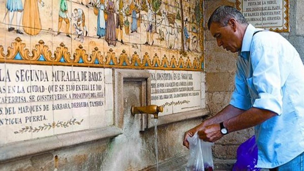 Un hombre coge agua del grifo de la histórica fuente de la calle de la Portaferrissa, junto a la Rambla, ayer.