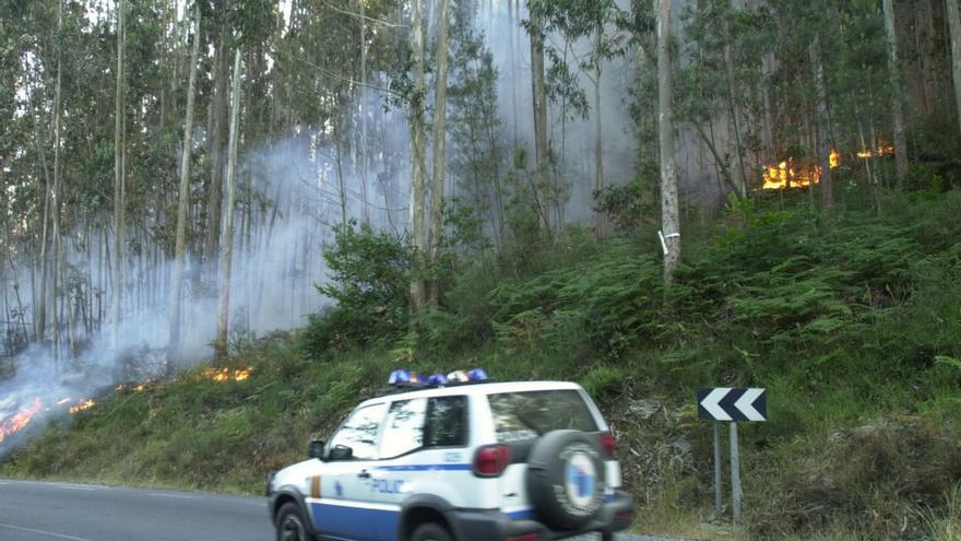 Una patrulla de la Policía autonómica llega a la zona donde se produjo un incendio. |   // L. O.