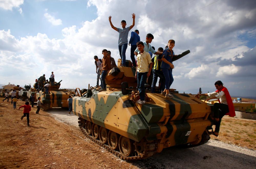 Boys stand on top of a Turkish army vehicle as a ...