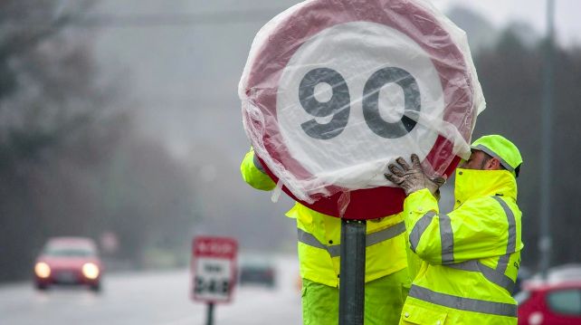 Dos operarios protegen una señal de velocidad en una carretera secundaria