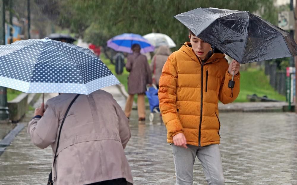 Viandantes tratan de protegerse de la lluvia, en el centro de Vigo