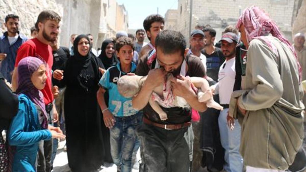 Un padre lleva el cadáver de su hijo, en Siria.