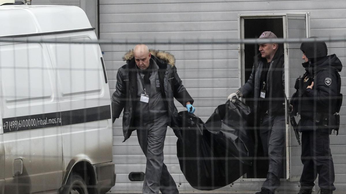 Personal médico transporta los cuerpos de las víctimas a los vehículos en la sala de conciertos Crocus City Hall.