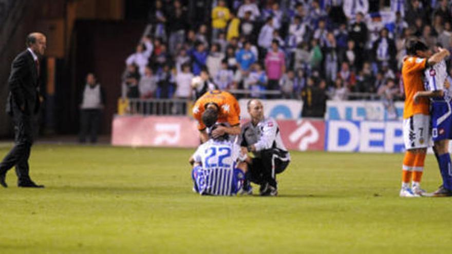 Lotina, en el césped, mientras los jugadores se lamentan por el descenso al final del partido. / Carlos Pardellas