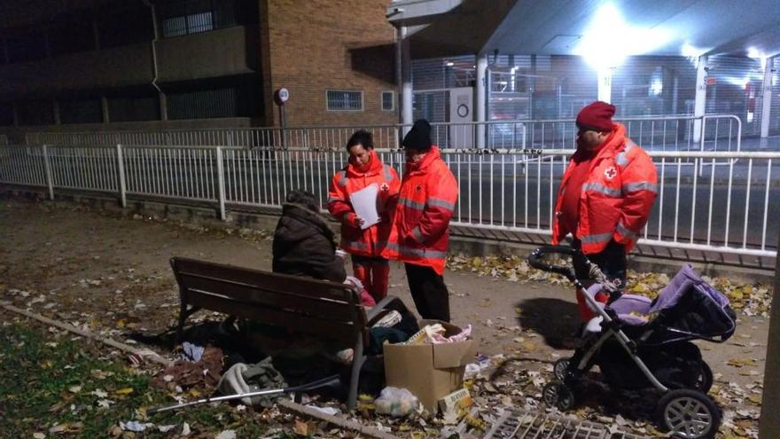 Voluntarios de la Cruz Roja atienden, anoche, a un sin hogar en el parque de l&#039;Estació de Gandia.