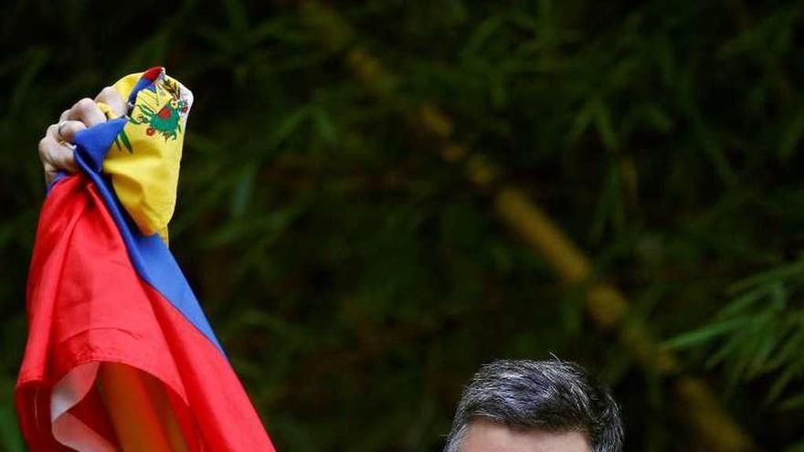 López saluda a sus simpatizantes, mostrando una bandera venezolana, a la entrada de su casa de Caracas. // Efe