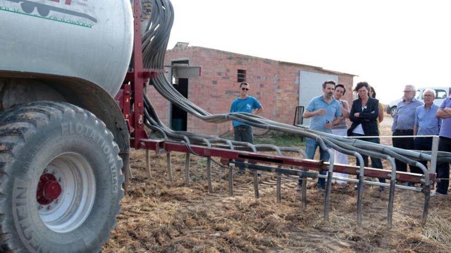 La consellera d&#039;Agricultura observant un tractor amb una cisterna que utilitza el sistema de tubs penjants en una finca de cereal d&#039;Albesa