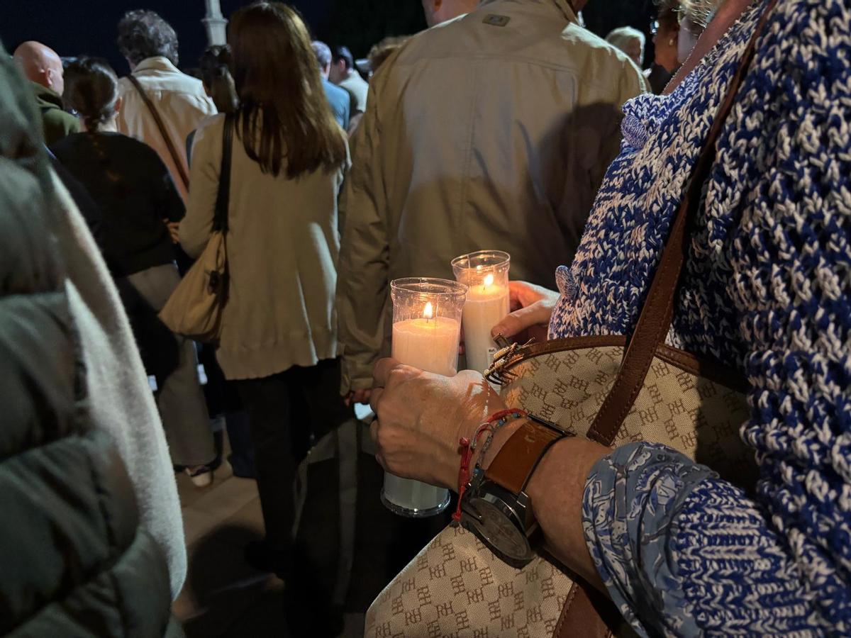 Una señora sujeta dos cirios para los homenajeados