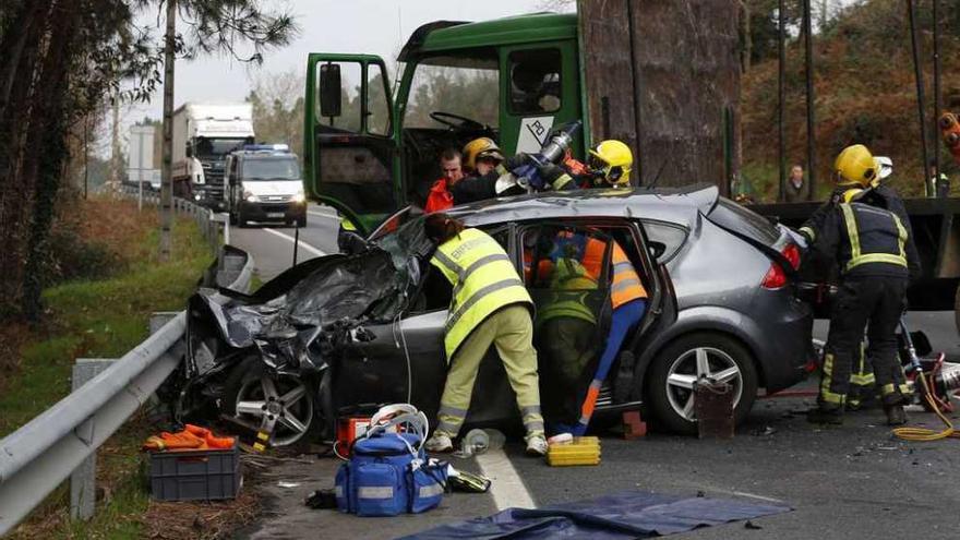 Un médico atiende a la víctima mientras los bomberos cortan el coche para excarcelarla. // Ricardo Grobas