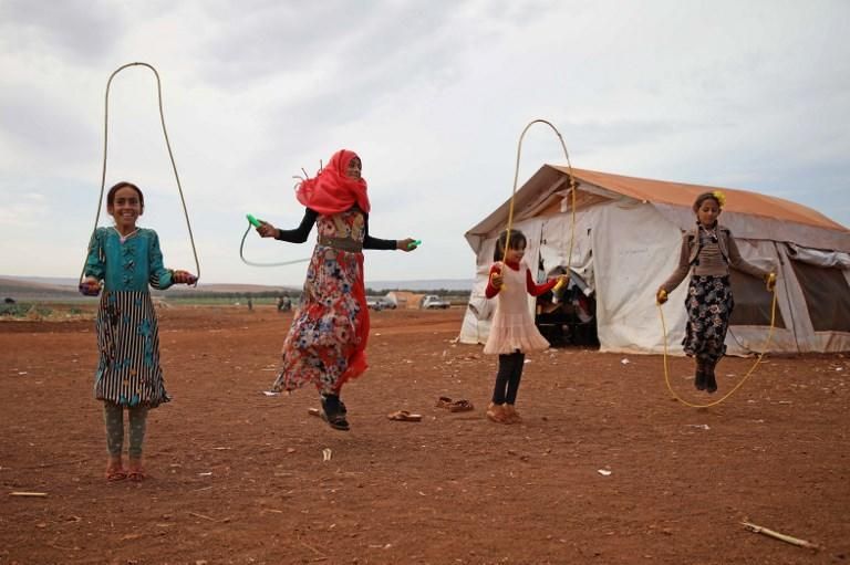 Unas niñas sirias saltan a la comba en un campo de refugiados al norte de Idlib.  / AFP PHOTO / Aaref WATAD