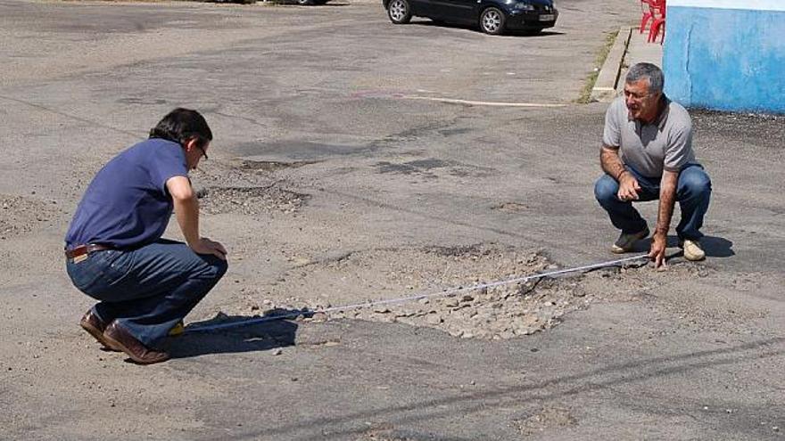 José Fernández Blanco y Pedro Castronuño miden las dimensiones de los baches existentes en la carretera a Castro.