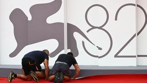 Workers set the red carpet at the Palazzo del Cinema ahead of the opening ceremony of the 82nd Venice Film Festival at Venice Lido, on August 26, 2025. (Photo by Stefano RELLANDINI / AFP)