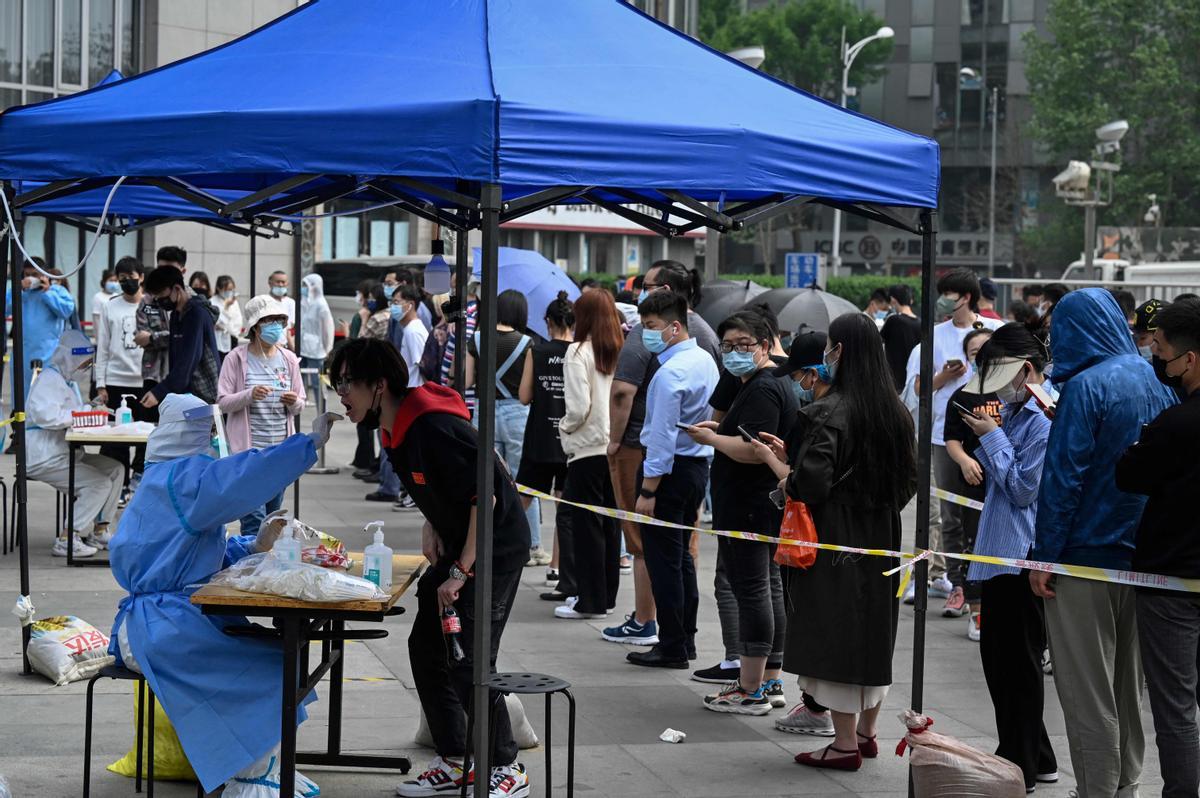 Una larga fila de ciudadanos espera para hacerse un test de covid en el exterior de una zona de oficinas de Pekín.