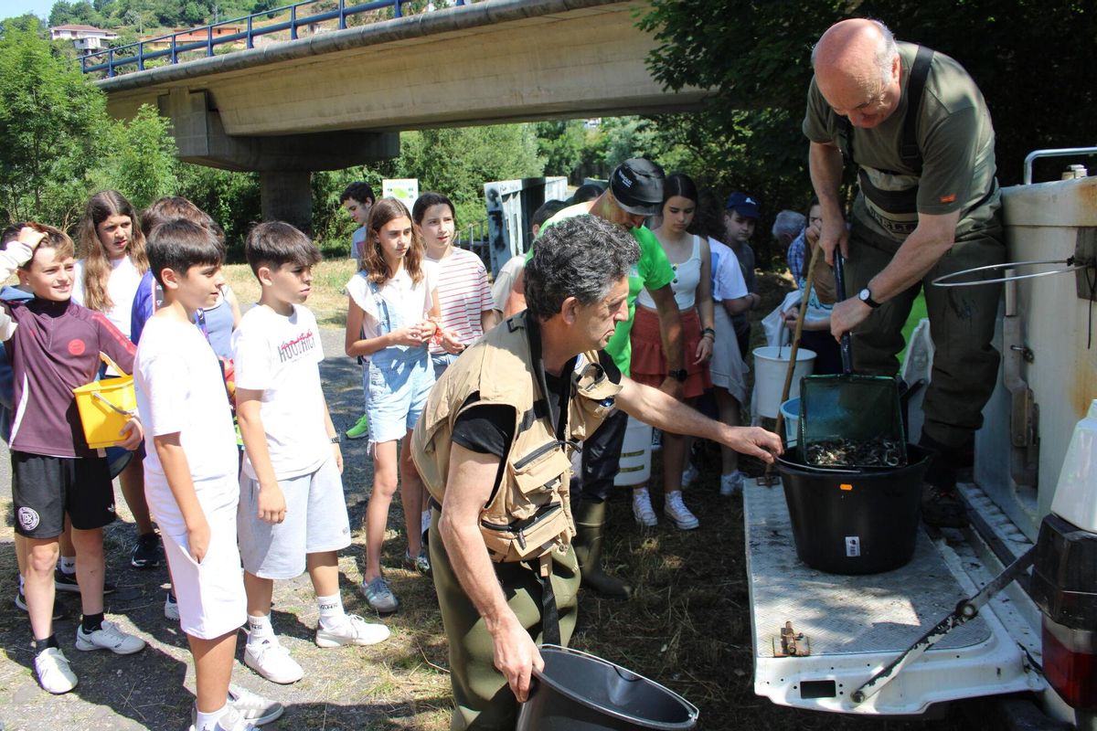 Los alumnos esperan porque les den los alevines para la suelta.