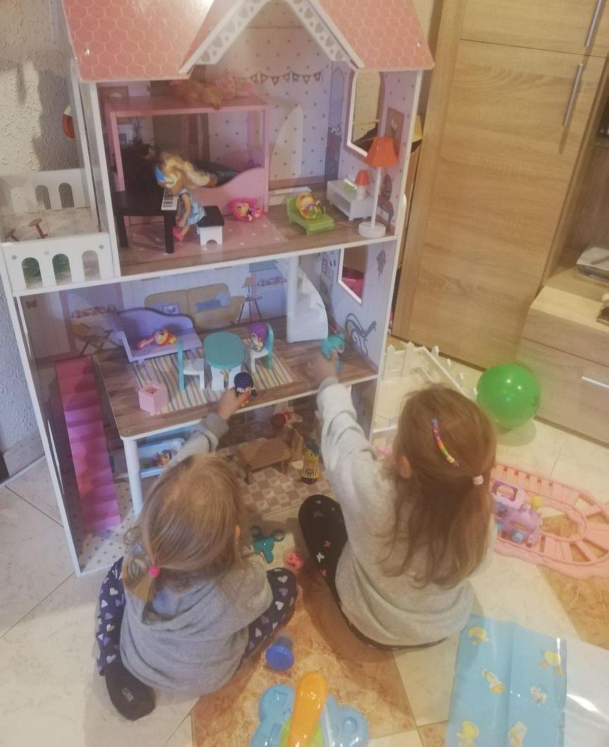Dos hermanas juegan con su nueva casa de muñecas. | Cedida