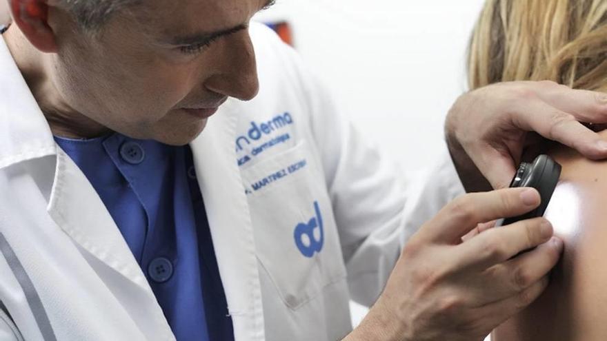 El doctor Martínez Escribano revisa la piel de una paciente