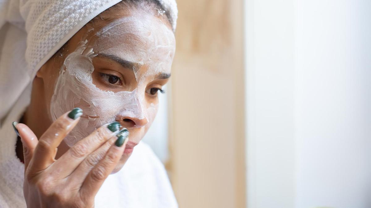Una mujer se aplica una crema facial.