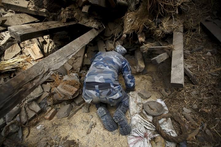 Miembros del equipo de rescate cavan para sacar el cuerpo atrapado de una mujer el día después del terremoto