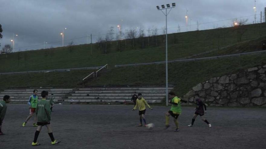 Niños de uno de los equipos del Eirís entrenan en el campo con los focos apagados.