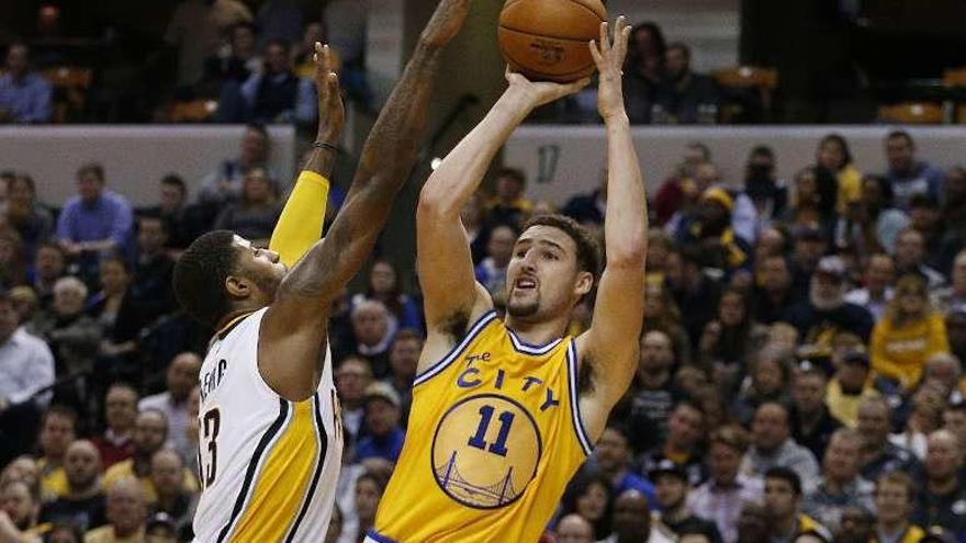 Klay Thompson lanza ante la oposición de un defensor.