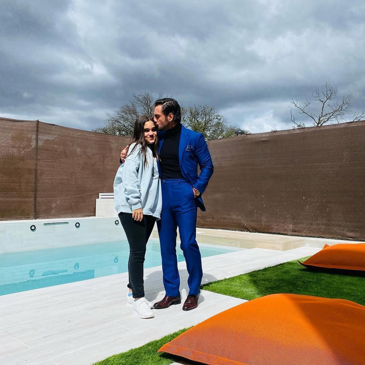 Bustamente junto a su hija con la piscina de su hogar de fondo