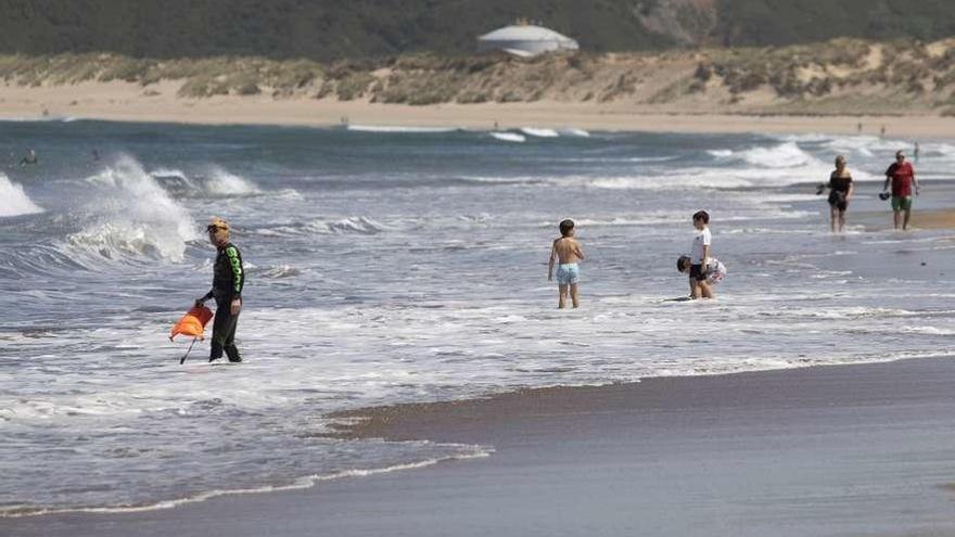 Paseantes y surfistas, ayer, en la playa de Salinas.