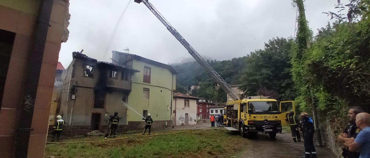 Los bomberos trabajan en la extinción del fuego declarado en el barrio de La Villa ante la presencia de policía y vecinos. | D. M.
