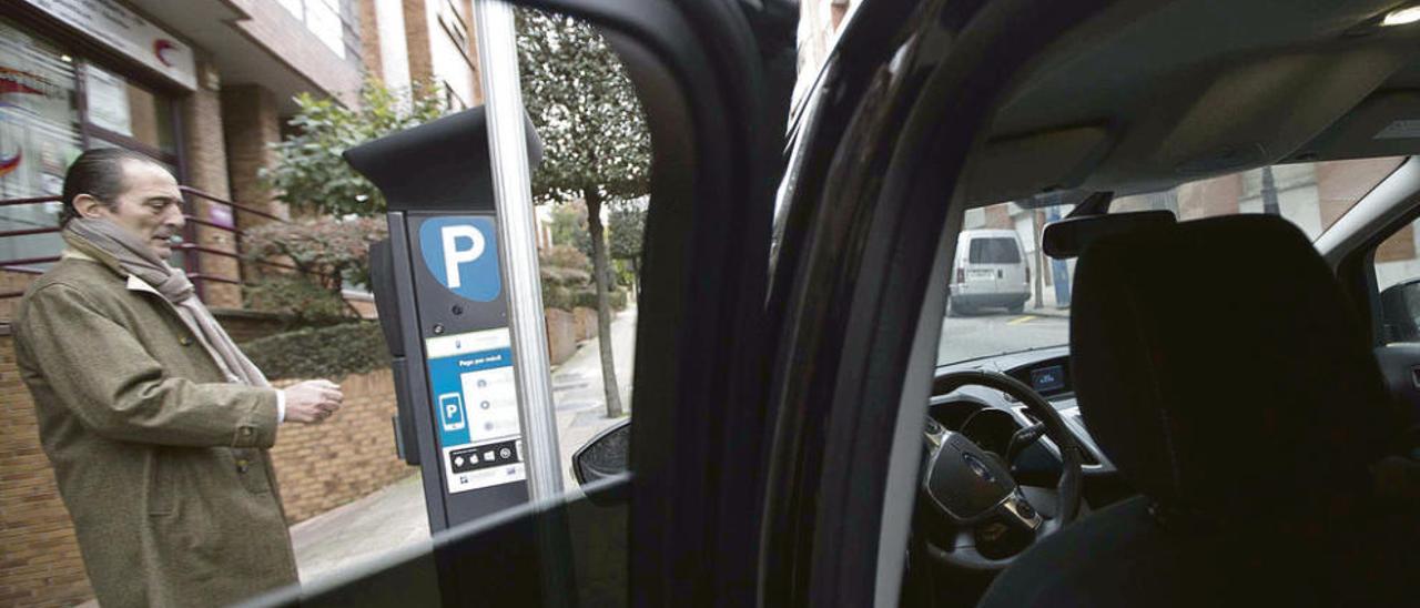 Un conductor saca el tique de la ORA en un parquímetro.