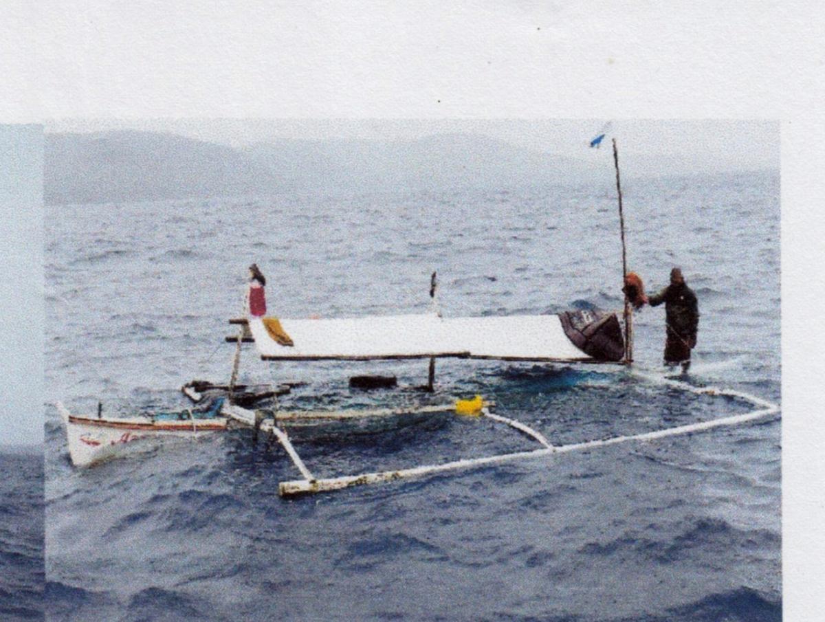 El patrón junto a la barcaza después de que se abriera una vía de agua en Filipinas.