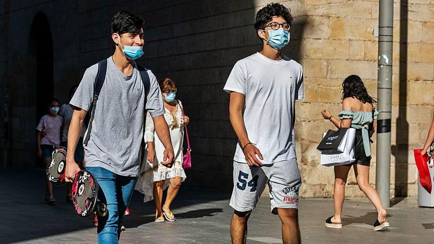 Dos jóvenes pasean ayer por el centro de Lleida, el de la izquierda, con la mascarilla mal colocada.