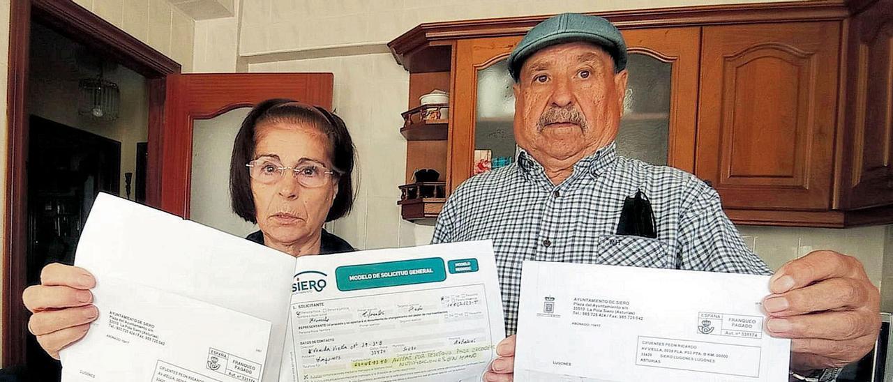 Juana Jara Manjoy y Ricardo Cifuentes, mostrando las facturas del agua y el escrito que dicen que enviaron al Ayuntamiento de Siero.