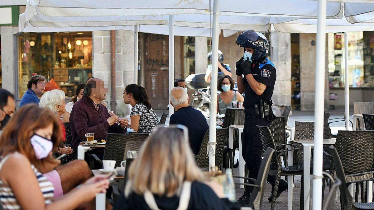 Un agentes de la Policía Local, ayer, realizando un control de aforo en una terraza de la plaza de Curros Enríquez