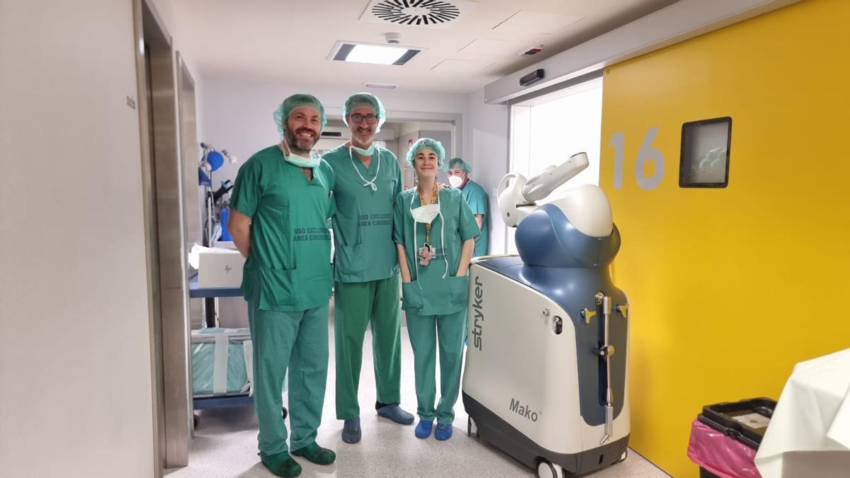 De izquierda a derecha, Alberto Mora, jefe de Traumatología y Cirugía Ortopédica del Chuac; Pablo Codesido, cirujano de la Unidad de Rodilla; e Inés López, MIR del servicio, junto al robot Mako, en el Hospital Universitario de A Coruña (Chuac).