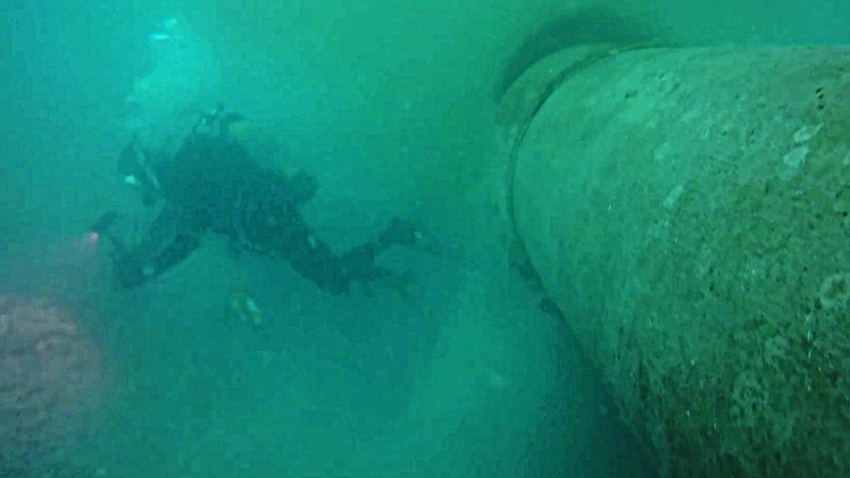 La gran tubería submarina, junto a un buzo, en uno de los puntos fracturados por donde se sale el agua.