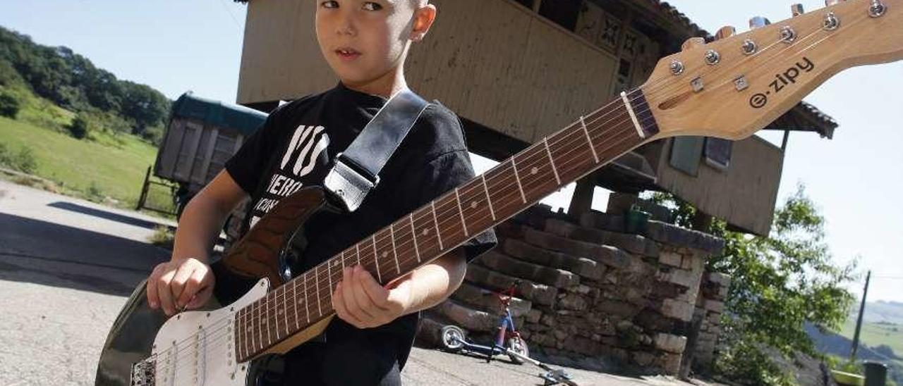 Illán Suárez, con la guitarra que tocará algún día, delante del hórreo de su casa.