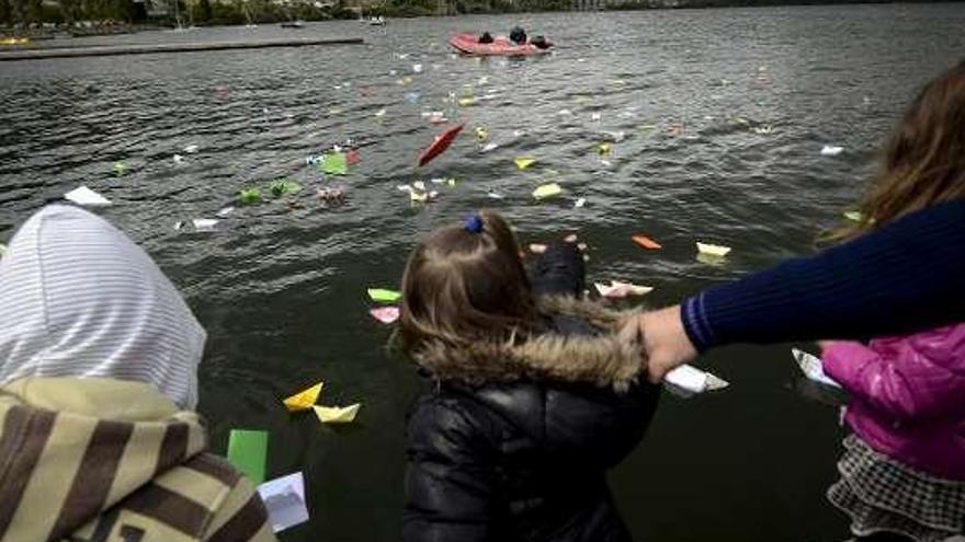 Una niña arroja un barco, ayer, al río Miño. / efe