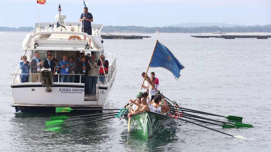 Los tripulantes de Samertolameu ondean la bandera que les acredita como vencedores de la Bandera Virxe do Carme de O Grove. // M.Muñiz